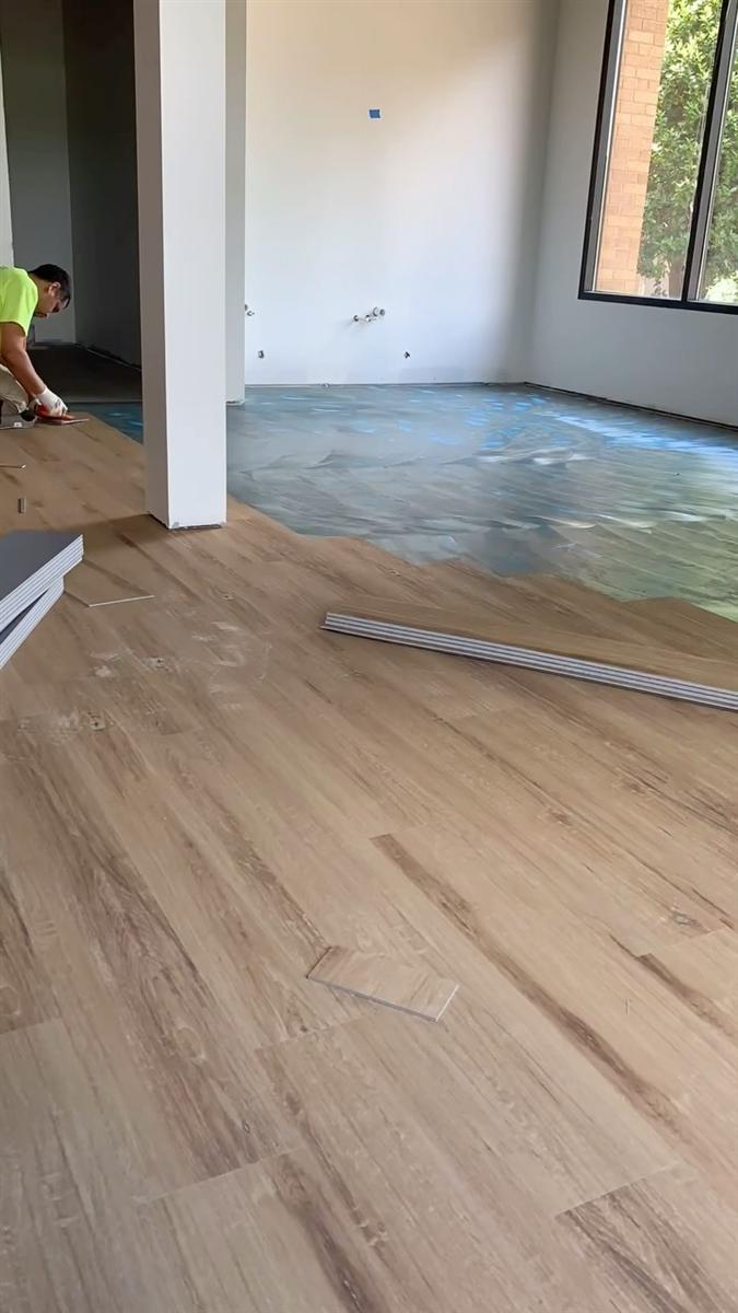 MB3 installer laying glue-down LVP over adhesive