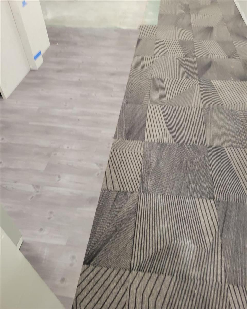 Grey LVP meeting patterned carpet tile